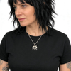 Woman wearing a black t-shirt with a necklace featuring a devil heart pendant on a white background