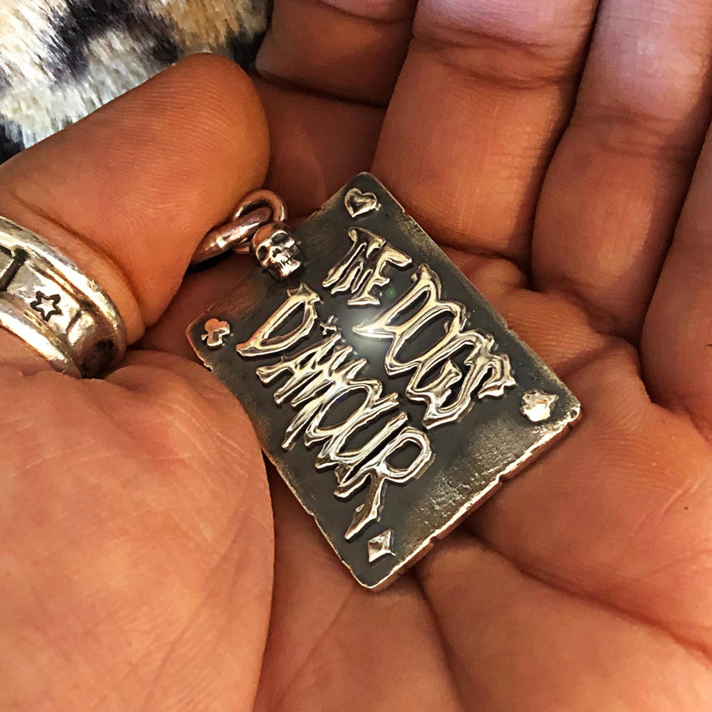 Hand holding the Dogs D'Amour pendant.