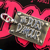 Dogs D'Amour pendant on top of red Dogs D'Amour logo.