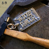 closeup on dogs d'amour pendant on work bench with tools.