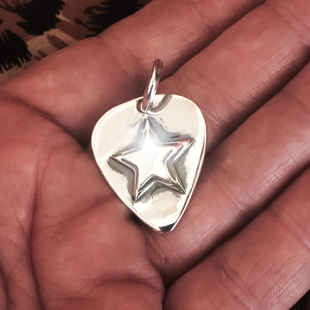 Silver Star Guitar Pic Pendant in a hand. 
