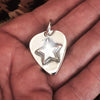 Silver Star Guitar Pic Pendant in a hand. 