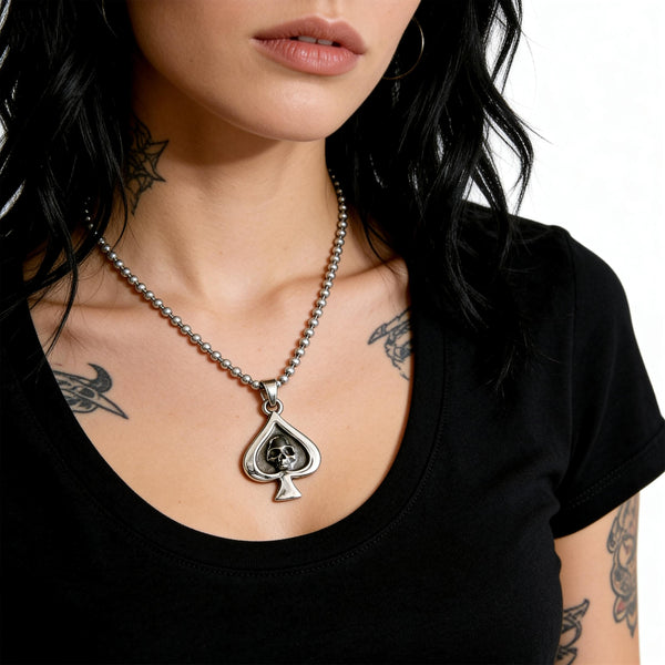 Necklace with a spade-shaped pendant featuring a skull on a person wearing a black shirt.