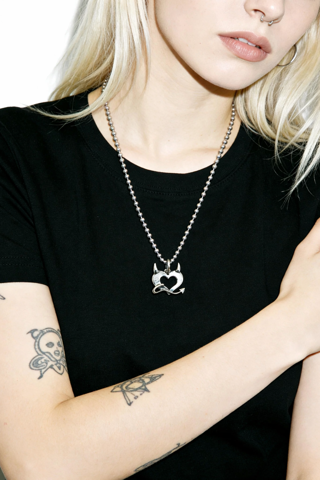 Person wearing a black t-shirt and a necklace with a devil heart pendant.