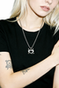 Person wearing a black t-shirt and a necklace with a devil heart pendant.