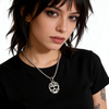 Woman wearing a black t-shirt with a skull pendant necklace on a white background