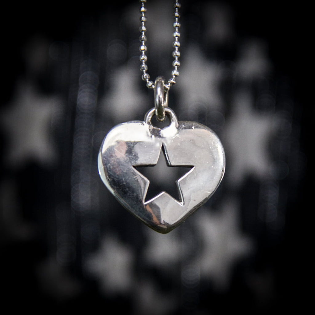 Silver heart-shaped pendant with a star cutout on a blurred starry background