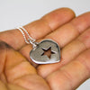 Silver necklace with a heart-shaped pendant featuring a star design held in a hand.