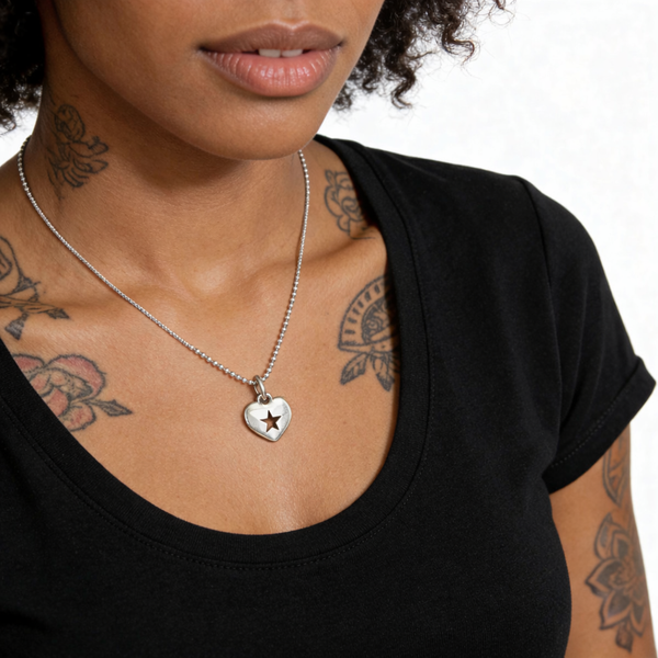Person wearing a black top with a silver necklace featuring a heart pendant with a star.