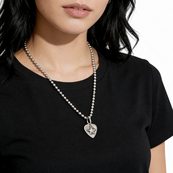 Person wearing a black shirt with a silver necklace featuring a guitar pic pendant with a star. 