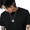 Person wearing a black t-shirt with a silver chain necklace featuring a true love double skull heart pendant.